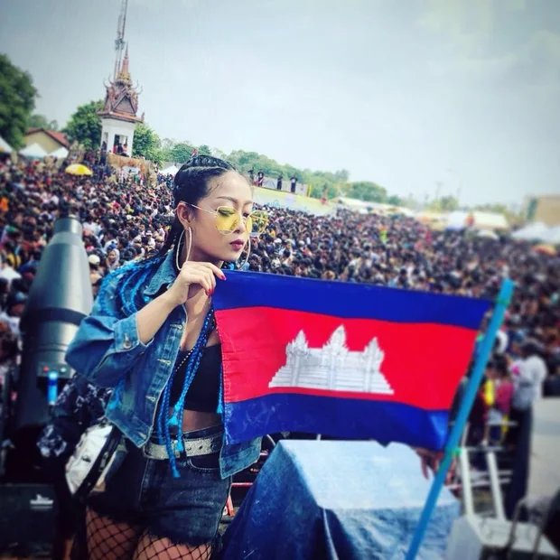 DJ VOCKA holding the Cambodian flag on stage before a provincial festival crowd